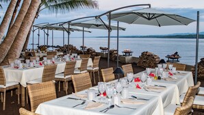 An outdoor dining area with tables set for a meal, overlooking a body of water.