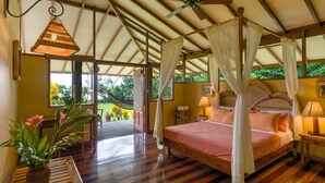 A spacious bedroom with a large bed, a ceiling fan, and a view of the outdoors.