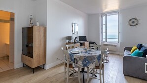 Un salon moderne avec une table à manger, un canapé gris et une grande fenêtre donnant sur un beau paysage.