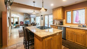 A spacious kitchen with wooden cabinets, granite countertops, and a central island. - A Lovely home, Pet Friendly, Hot Tub & National Forest (Black Butte Ranch)