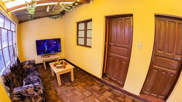 Una stanza con pavimento in legno, un divano, una televisione e due porte di legno.