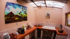 Una cucina compatta con lavello, tostapane e un quadro che raffigura un paesaggio.