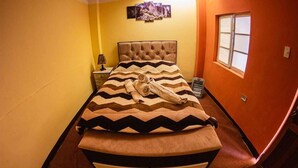 Una camera da letto con un letto, un comodino, una lampada, una finestra e un quadro appeso al muro.