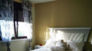 A bedroom with a bed, nightstands, a rug, and curtains. - Cottage (Vilaboa)