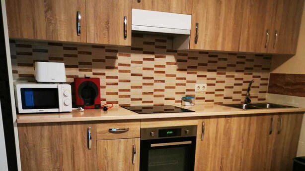 A kitchen with wooden cabinets, a microwave, a coffee maker, and a dishwasher. - Cottage (Vilaboa)