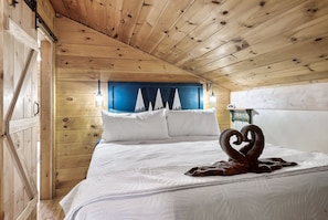 Un dormitorio de cabaña de madera con una cama, almohadas y una lámpara de pared.
