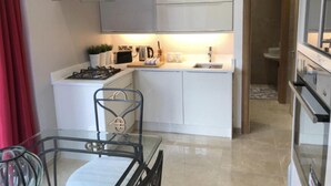 A compact kitchen with white cabinets, a gas stove, a coffee maker, and a sink. - Luxurious Studio Apartment in Fahan, Co Donegal (Fahan)