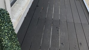 A wooden deck with a metal railing, a small potted plant, and a view of a grassy area. - Luxurious Studio Apartment in Fahan, Co Donegal (Fahan)