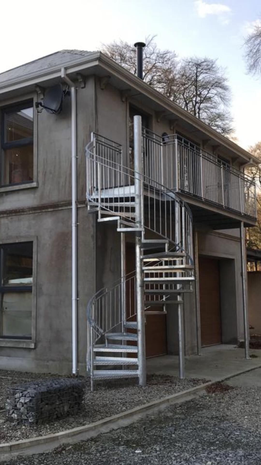 Un edificio de dos pisos con una escalera metálica que lleva a un balcón.