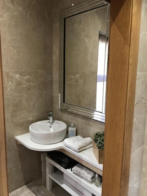 A bathroom with a round sink, a mirror, and a towel rack.