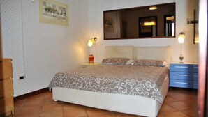 A bedroom with a bed, a nightstand, a dresser, a mirror, and wall-mounted lights. - Villa Saha wonderful villa (Itri)