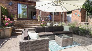 An outdoor patio with a sofa set, a table, and an umbrella.