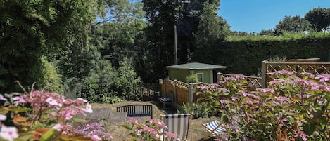 A garden with a small wooden structure, a bench, and various plants.