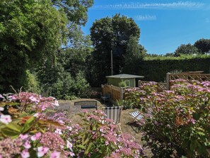 A garden with a small wooden structure, a bench, and various plants. - Hillcrest (Wrexham)