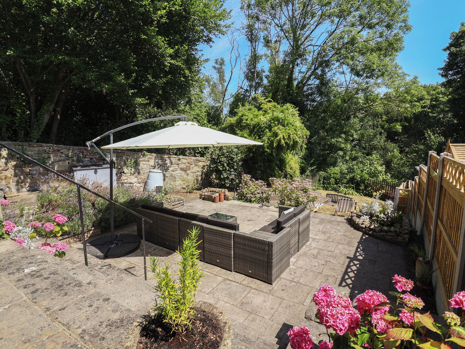 A patio area with a seating arrangement, a pergola, and a stone wall.