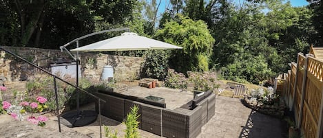 A patio area with a seating arrangement, a pergola, and a stone wall.