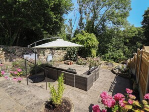 A patio area with a seating arrangement, a pergola, and a stone wall. - Hillcrest (Wrexham)