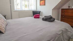A bedroom with a bed, a chair, a dresser, and a window with blinds. - Hillcrest (Wrexham)