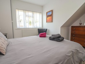 A bedroom with a bed, a chair, a dresser, and a window with blinds. - Hillcrest (Wrexham)