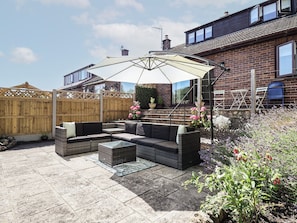 A patio with outdoor furniture, a pergola, and a brick house in the background. - Hillcrest (Wrexham)