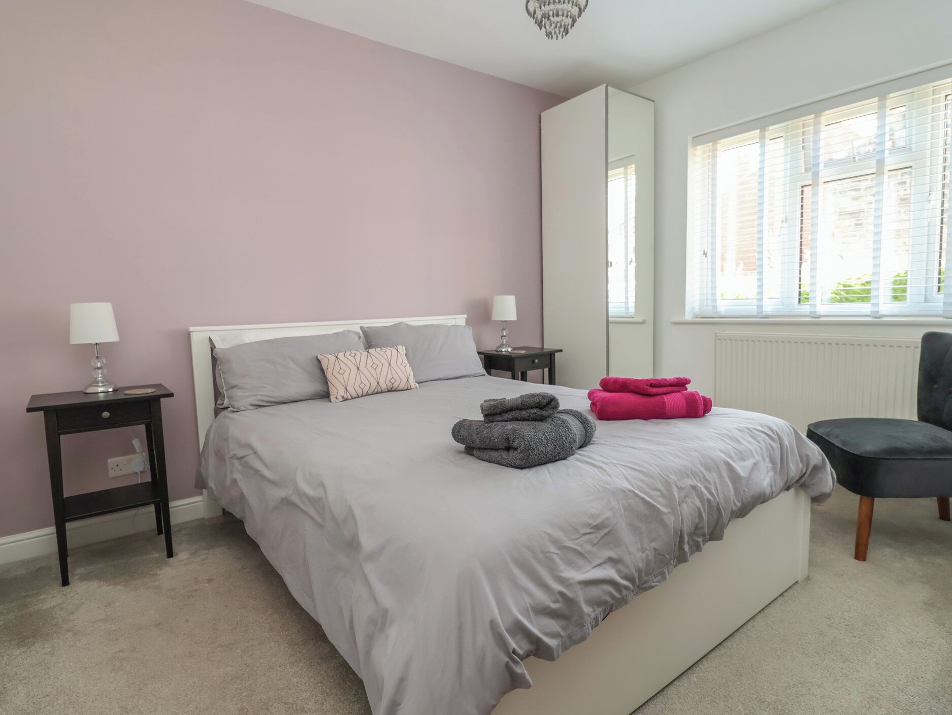 A bedroom with a bed, bedside tables, a chair, and a window.