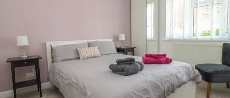 A bedroom with a bed, bedside tables, a chair, and a window.