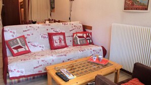 Una sala de estar acogedora con un sofá estampado, una mesa de centro de madera y un radiador.