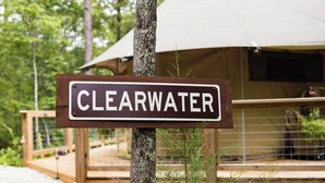 Un letrero que dice 'CLEARWATER' frente a una terraza de madera y una tienda de campaña.