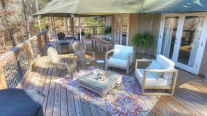 A wooden deck with outdoor furniture, including chairs and a sofa, under a large umbrella.
