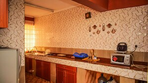 Una cocina con papel tapiz estampado, armarios de madera, un microondas y un lavamanos.