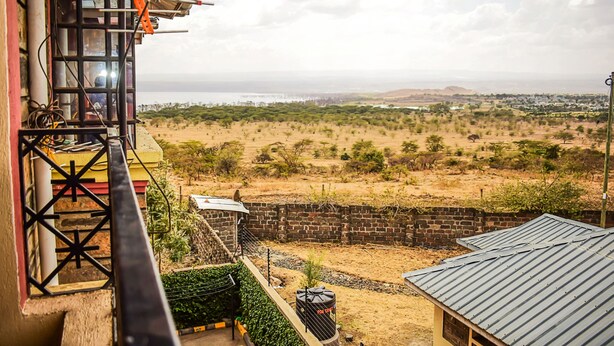 Vista desde un balcón sobre un paisaje seco con vegetación escasa y colinas distantes.