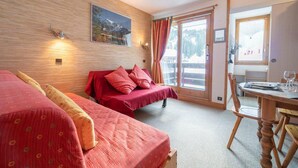 Ein Hotelzimmer mit zwei Betten, einem Esstisch und einem großen Fenster mit Bergblick.