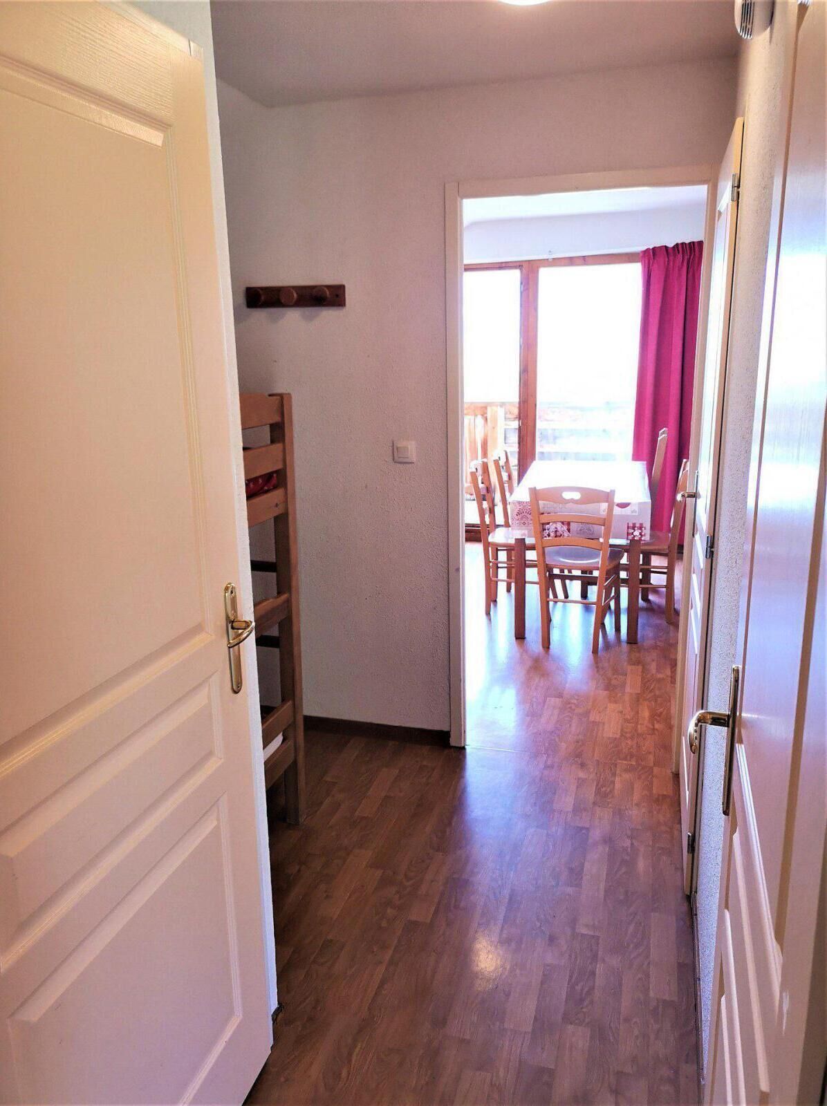 Een hal met houten vloer die uitkomt op een eetgedeelte met een tafel en stoelen.