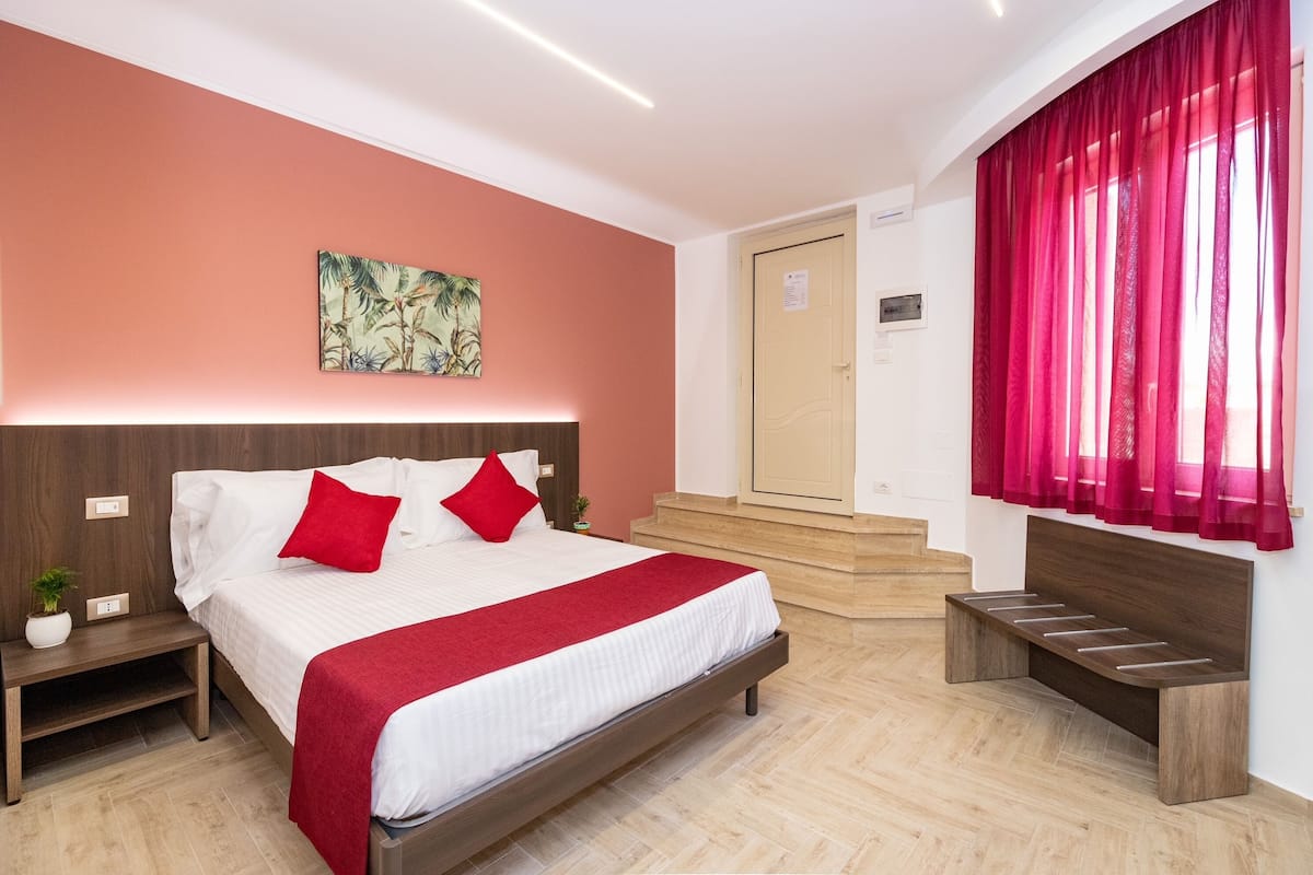 Ein modernes Hotelzimmer mit einem Bett, einem Nachttisch, einer Bank, einer Treppe und einer Tür.