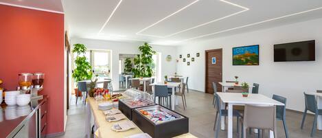 A modern dining area with a buffet setup, including various food items and a beverage station.