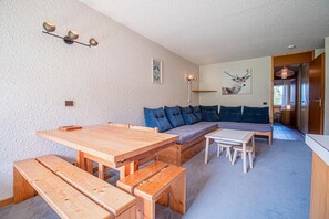 A cozy living room with a wooden table, benches, a sofa, and a small dining area. - 50m from shops, 2nd floor, view ski slopes, balcony, tv, ski locker, 32m², Valmorel (Valmorel)