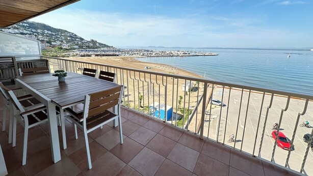 A balcony with a view of the sea, a table with chairs, and a small potted plant. - Agi Avenida 5A Apartamento for rent in Roses Girona. (Roses)
