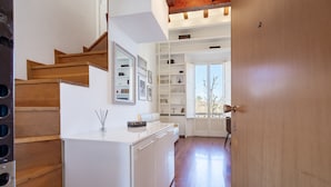 A modern kitchen with wooden stairs, white cabinetry, and a built-in bookshelf.