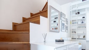 A modern interior with wooden stairs, a white counter, and a built-in shelving unit.
