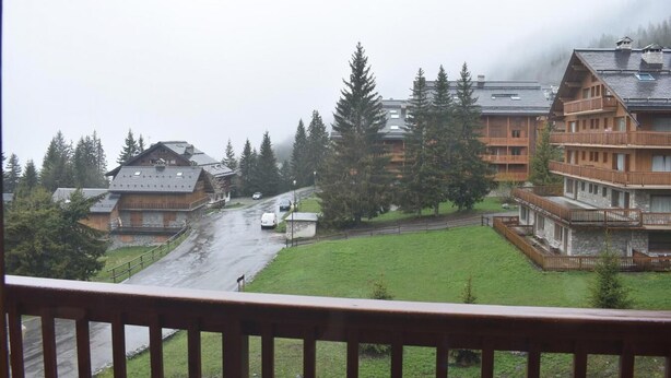 A mountainous village with wooden buildings, a wet road, and a grassy area. - 20m from ski slopes, 2nd floor, tv, ski locker, 19m², Méribel (Méribel - Les Allues)