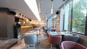 Un restaurant moderne doté d’un sol en marbre, de plusieurs espaces de détente et de grandes fenêtres offrant une vue sur l’extérieur.