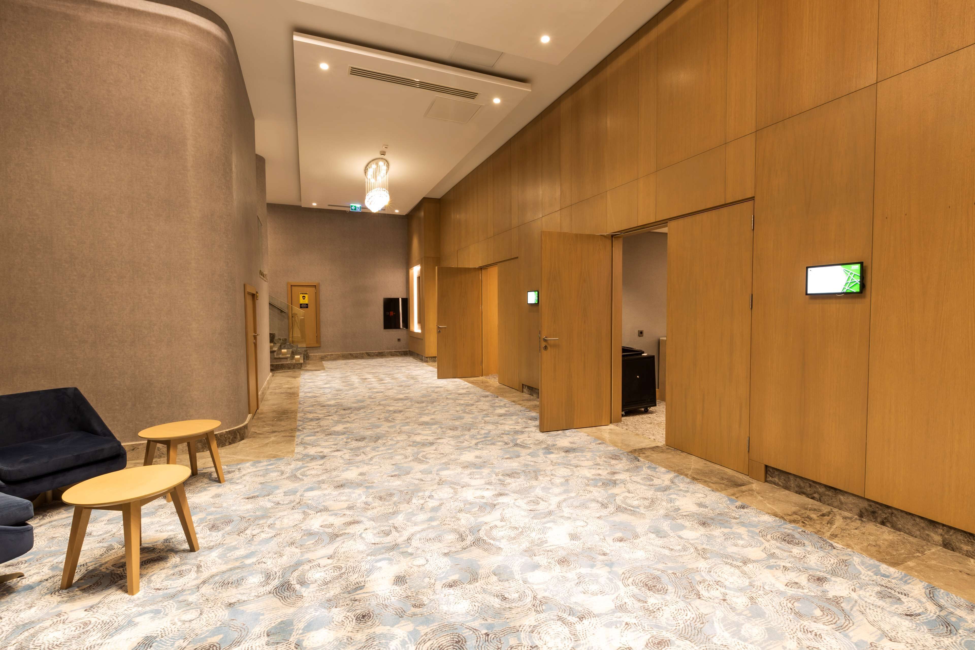 Un vestíbulo de hotel con alfombra estampada, paredes de madera y un mostrador de recepción.