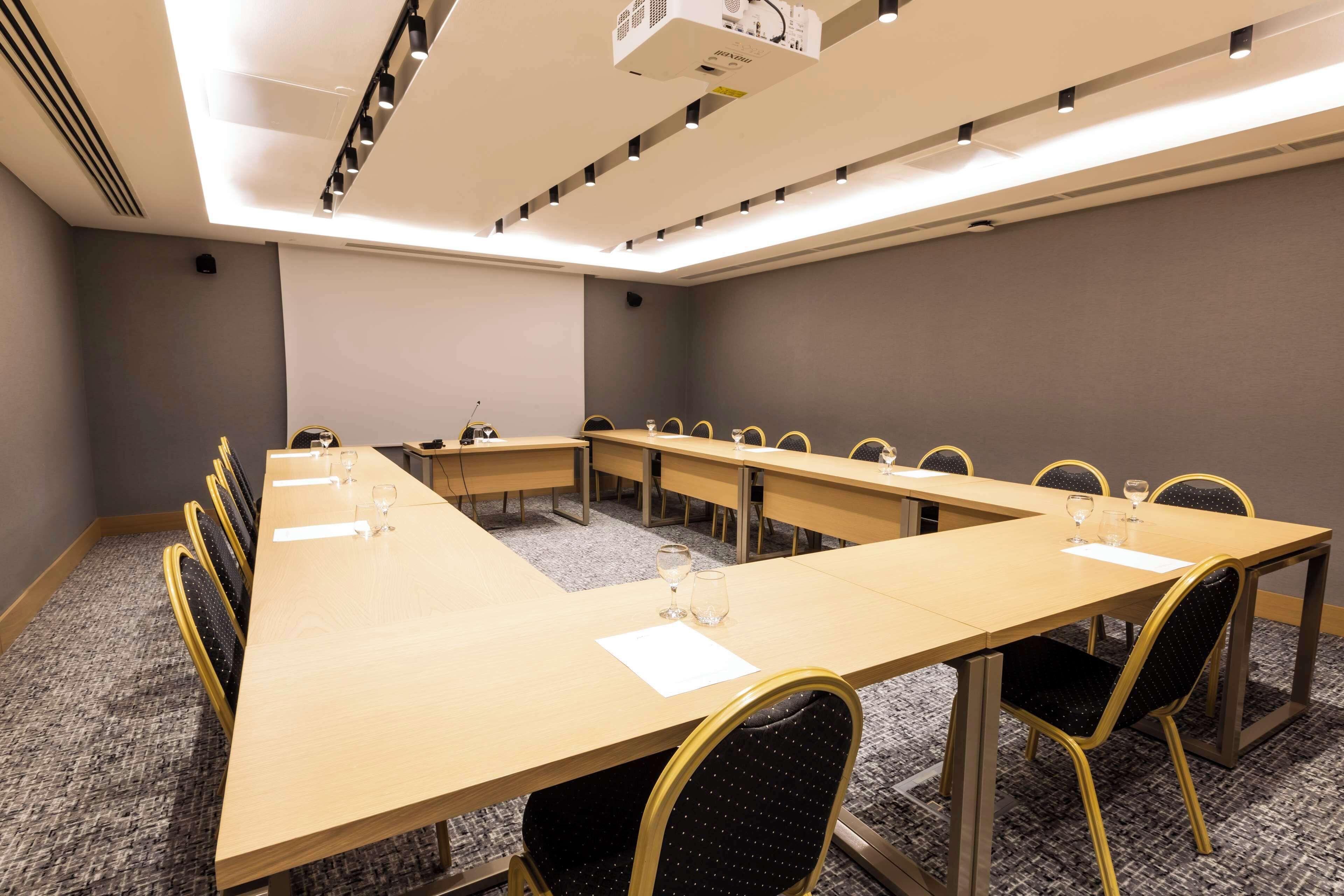 A conference room with a long table, multiple chairs, and a projector.