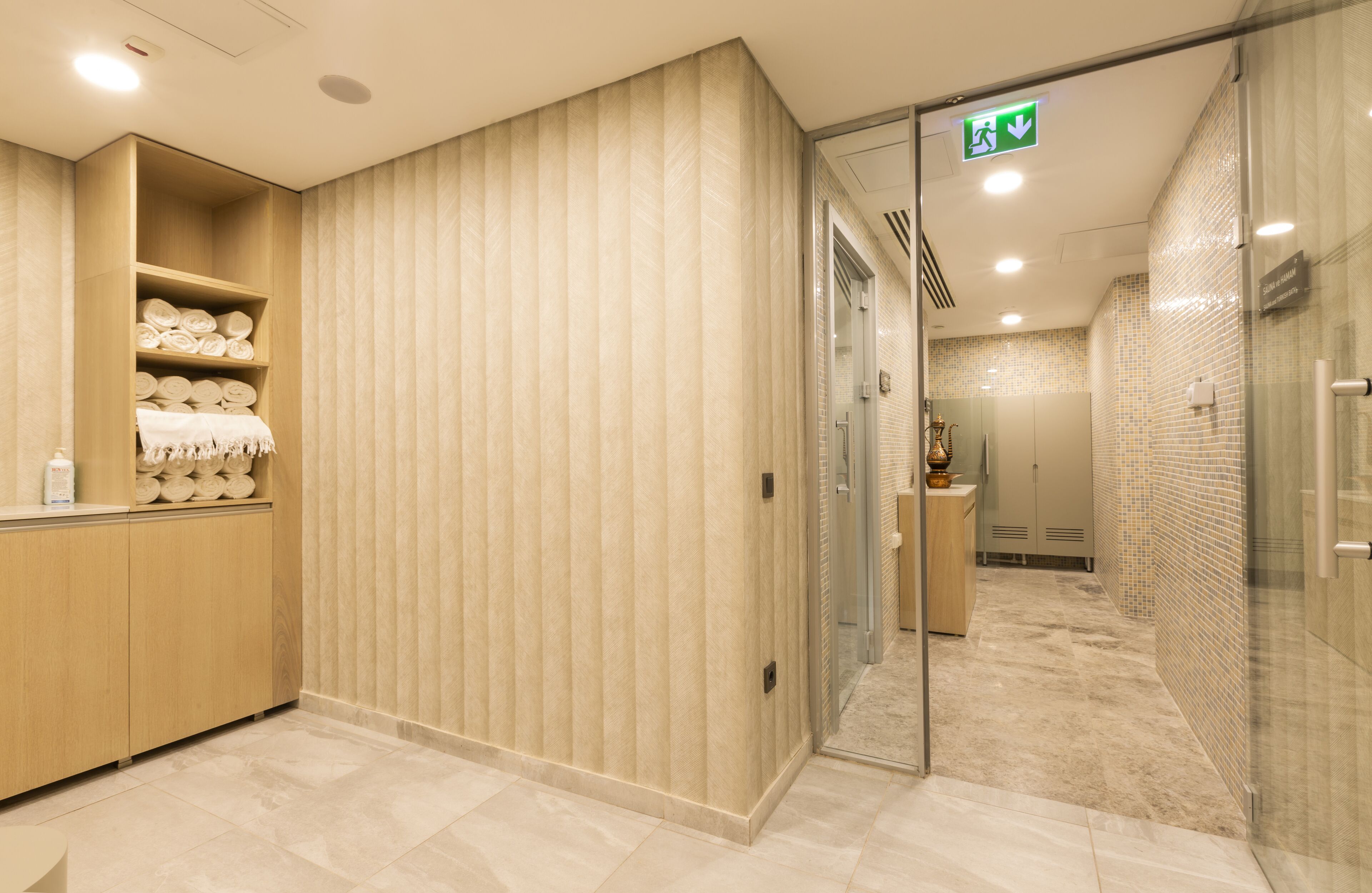 A modern bathroom with a wooden vanity, a glass shower enclosure, and a tiled floor.
