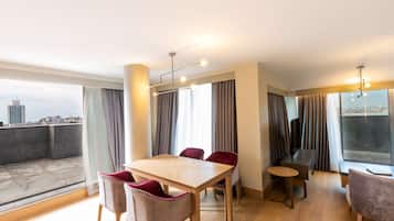 Uma sala de jantar moderna com mesa de madeira e cadeiras vermelhas, janelas amplas com cortinas e vista para a cidade.