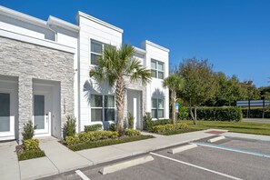 A modern building with a stone facade, large windows, and a well-maintained lawn. - Hidden Forest 3 Bedroom Vacation Home (2020) (Clermont)