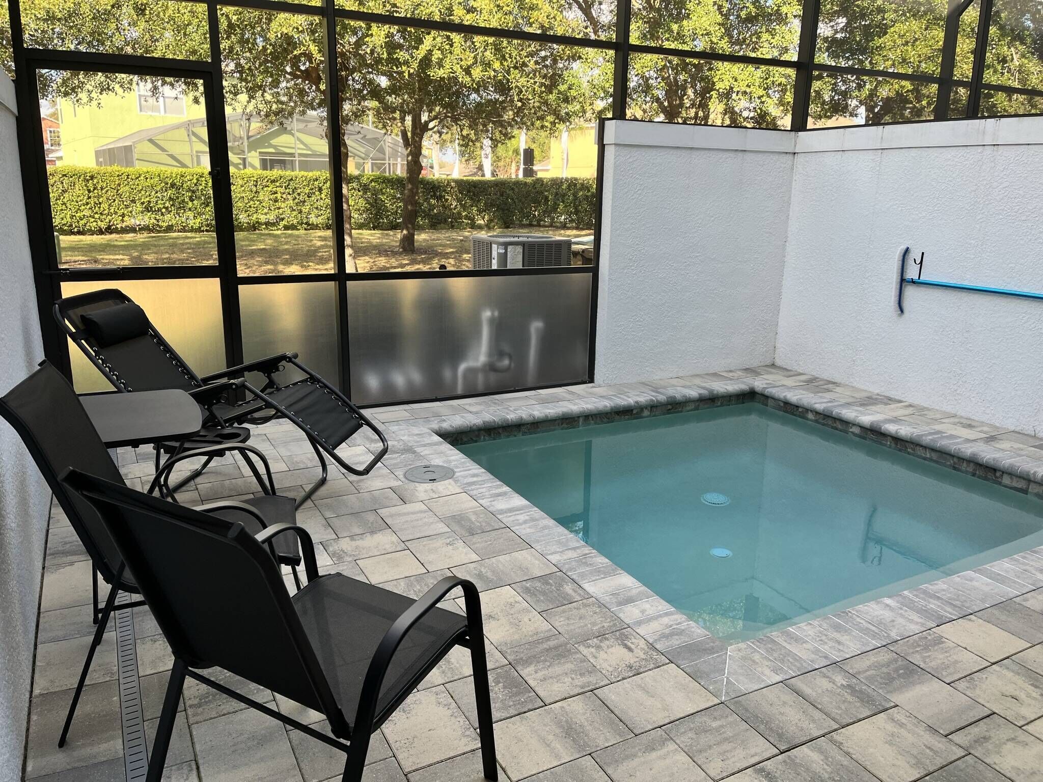 Un espace piscine intérieur doté d’un sol carrelé, d’une petite piscine et de deux chaises longues noires.