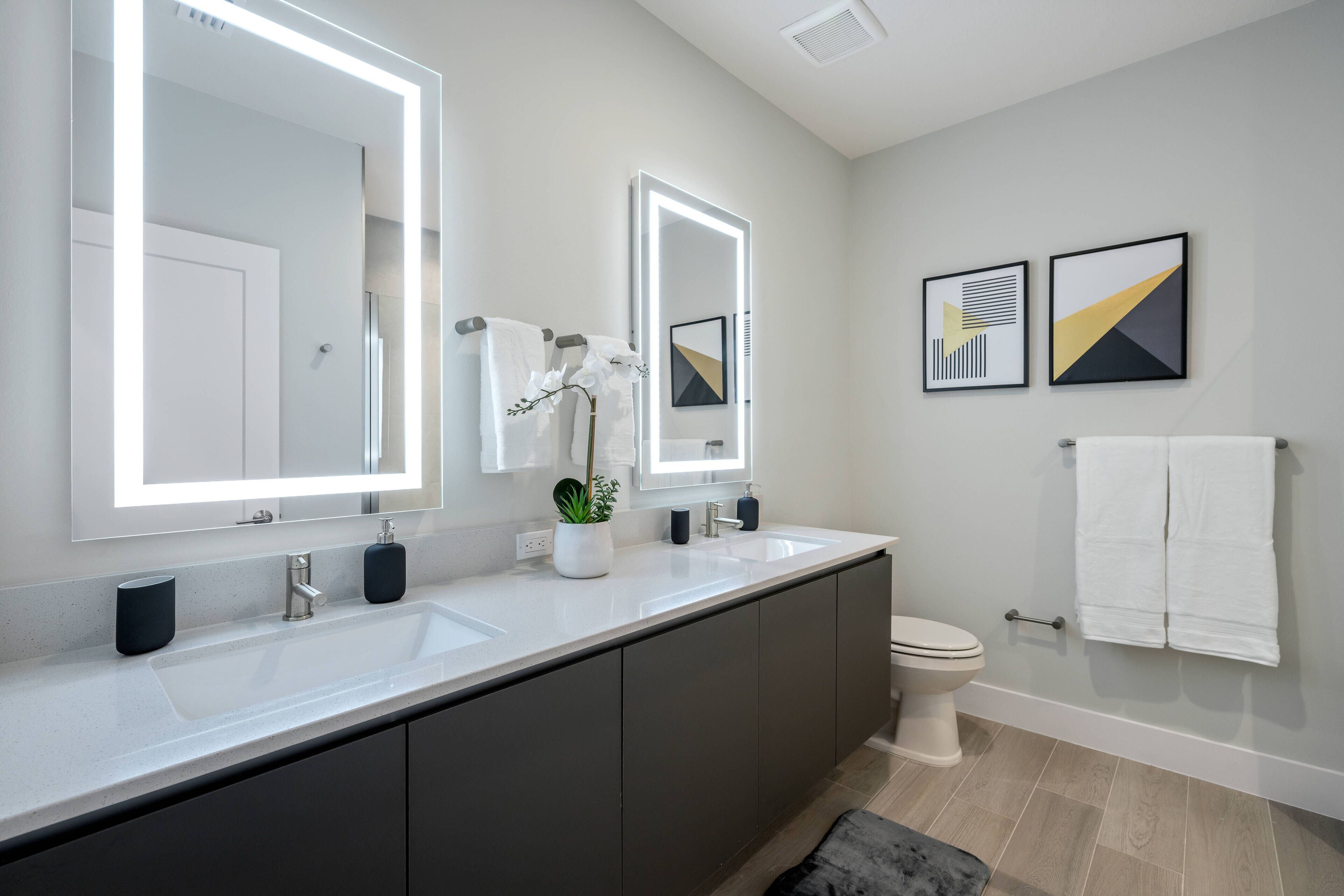 Een moderne badkamer met twee wasbakken, een grote spiegel, een toilet en een bad.