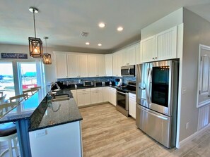 A modern kitchen with white cabinetry, stainless steel appliances, and a granite countertop.