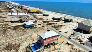 An aerial view of a beachside area with multiple buildings, including a prominent red building with a blue pool in the foreground, and a road leading to the beach. - Private Pool - Great views!  Fort Morgan (Gulf Shores)